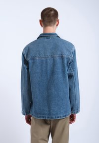 Giacca di jeans blu con colletto classico, maniche lunghe e vestibilità rilassata. Caratterizzata da dettagli di cucitura e un interno foderato.