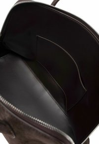 Brązowa skórzana torebka z zamkiem błyskawicznym, wyposażona w gładkie wnętrze, małą kieszonkę i staranne detale przeszyć.