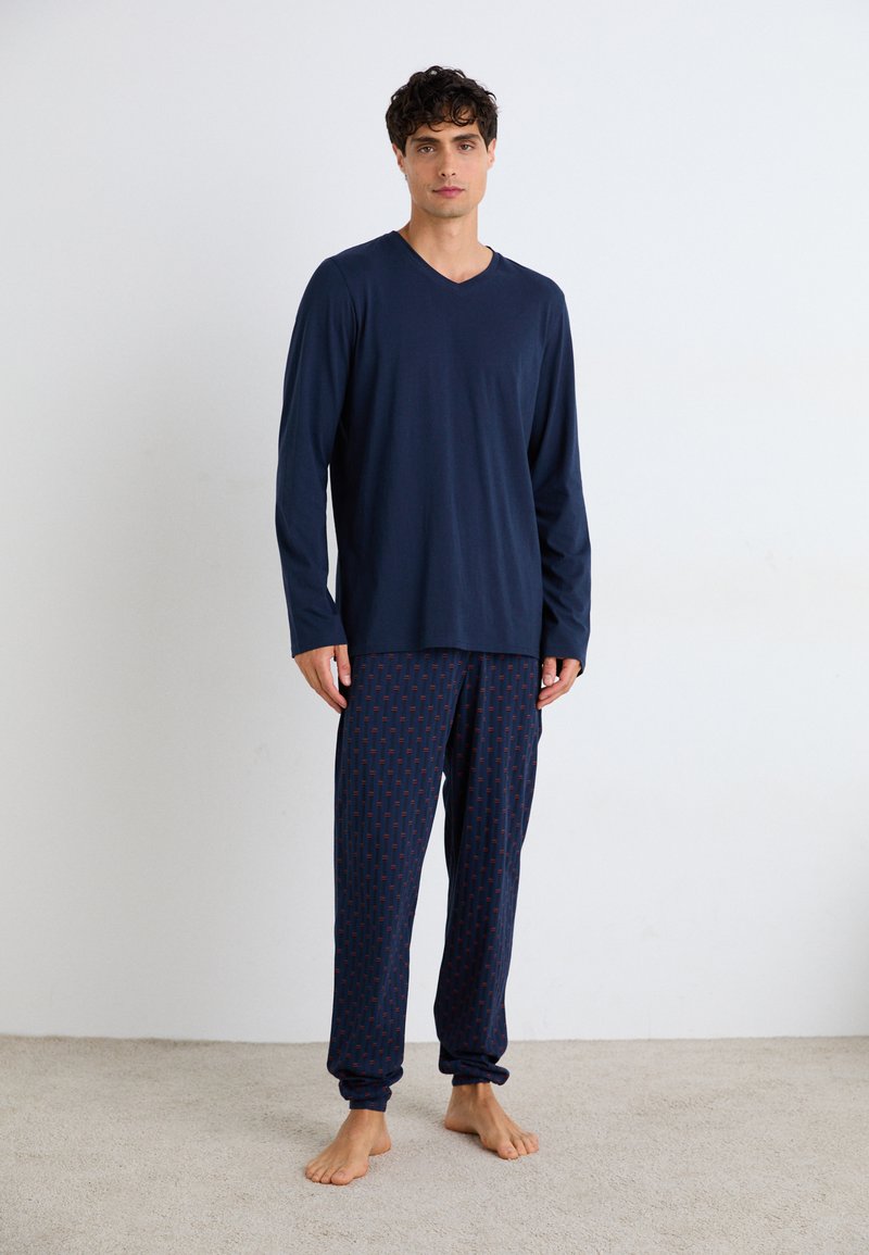 Marineblauw langetermijn T-shirt met V-hals, gecombineerd met gestreepte pyjamabroek in donkerblauw, met een geometrisch ontwerp in rood. Lichtgewicht stof, relaxte pasvorm.