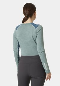 Długi rękawek w jasnym niebiesko-zielonym kolorze z ciemnoniebieskimi panelami na ramionach, dopasowany krój, teksturowana tkanina, z białymi paskami na rękawach.