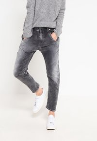 Gray, faded jeans with a relaxed fit, five pockets, and subtle whiskering details, paired with white sneakers. Soft denim texture.