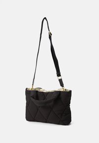 Schwarze, gesteppte, rechteckige Schultertasche mit kurzen Griffen und verstellbarem langen Gurt, beiger, gemusterter Innenfutter sichtbar an der Öffnung.