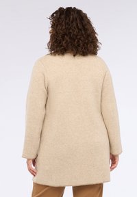 Beige dlouhý kabát z vlněné směsi s texturovaným pletem, rovného střihu a dlouhými rukávy, zobrazený zezadu.