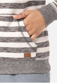 Sudadera a rayas gris y blanca con un bolsillo delantero y puños acanalados. Presenta una pequeña etiqueta de marca que destaca un tejido texturizado.