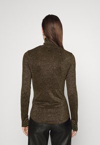 Brauner, langärmeliger Rollkragenpullover mit metallic Schimmer. Figurbetontes Design und glatte Textur, mit einem subtilen Logo nahe dem Hals.