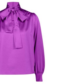 Blusa in raso viola con colletto alto, grande dettaglio in papillon e maniche lunghe a sbuffo, caratterizzata da una texture liscia e lucida e una vestibilità ampia.
