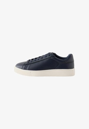 Pantof sport de piele bleumarin cu talpă joasă, șireturile negre și talpă de cauciuc albă, vedere laterală pe fundal alb simplu.