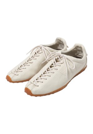Zapatos casuales de cuero color blanco roto con cordones, suelas de goma y costuras visibles, mostrados uno al lado del otro sobre un fondo blanco.