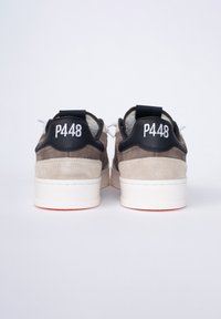 Sneaker in pelle scamosciata e pelle beige e marrone con una intersuola bianca e una suola arancione. Il tallone nero presenta "P448" in bianco.