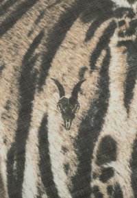 Bomuldsstof med dyreprint i sort og beige striber. Et centralt grafisk motiv af et sort gedeskulder er synligt midt i mønsteret.