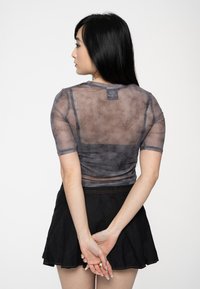Sheer gray t-shirt with short sleeves, featuring a textured design; paired with a black skirt. The fabric has a slightly mottled appearance.