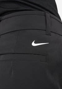 Pantalones cortos deportivos negros hechos de tela suave, con un bolsillo trasero y un logo blanco de Nike encima del bolsillo del lado derecho.