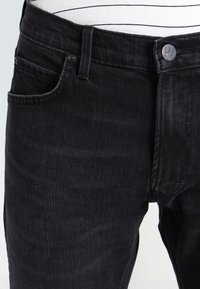 Černé džíny z denimu s klasickým designem pěti kapes, na pase knoflík s logem značky Lee a jemná textura látky.