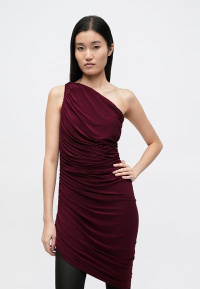 Bordó aszimmetrikus ruha, egy vállán redőzött textúrával és redőzött kialakítással, testhez simuló sziluettel és oldalsó sliccel.