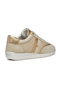 Baskets beiges avec un corps en maille texturée, des accents en daim, des détails métalliques dorés et une semelle en caoutchouc blanche. Lacets et marque visibles.