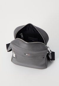 Borsa in pelle grigia con apertura con zip, tasche interne e foderatura in tessuto. Presenta una tasca frontale con zip e una tracolla regolabile.