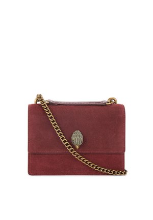 Czerwona zamszowa torebka na ramię z łańcuszkiem w kolorze złotym, z ozdobnym zapięciem w kształcie liścia oraz gładką teksturą.