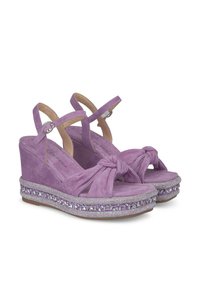 Sandali con zeppa in suede viola, dotati di un design con tracolla annodata, cinturini alla caviglia e un'applicazione di perline lungo il bordo della piattaforma.