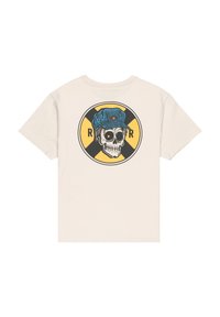 Camiseta con una calavera que lleva una gorra azul dentro de un diseño circular amarillo y negro con la letra R a cada lado, sobre un fondo crema.