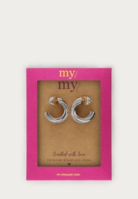 Edelstahl-Creolen mit geschwungenem Design und silberner Oberfläche, auf einer Seite mit einer Reihe klarer Steine. Präsentiert auf einer rosa Karte.