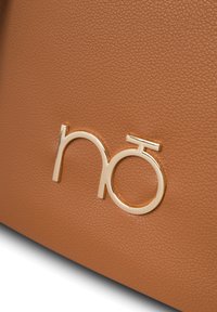 Bruine leren tas met textuur en een gouden logo-accent, met een gladde afwerking en een ronde vorm. Minimalistisch ontwerp met strakke lijnen.