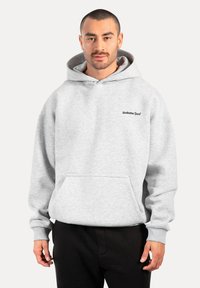 Felpa grigia con cappuccio, tasca frontale e logo 'Smilodax Sport'. Realizzata in materiale morbido con una vestibilità rilassata e oversize.