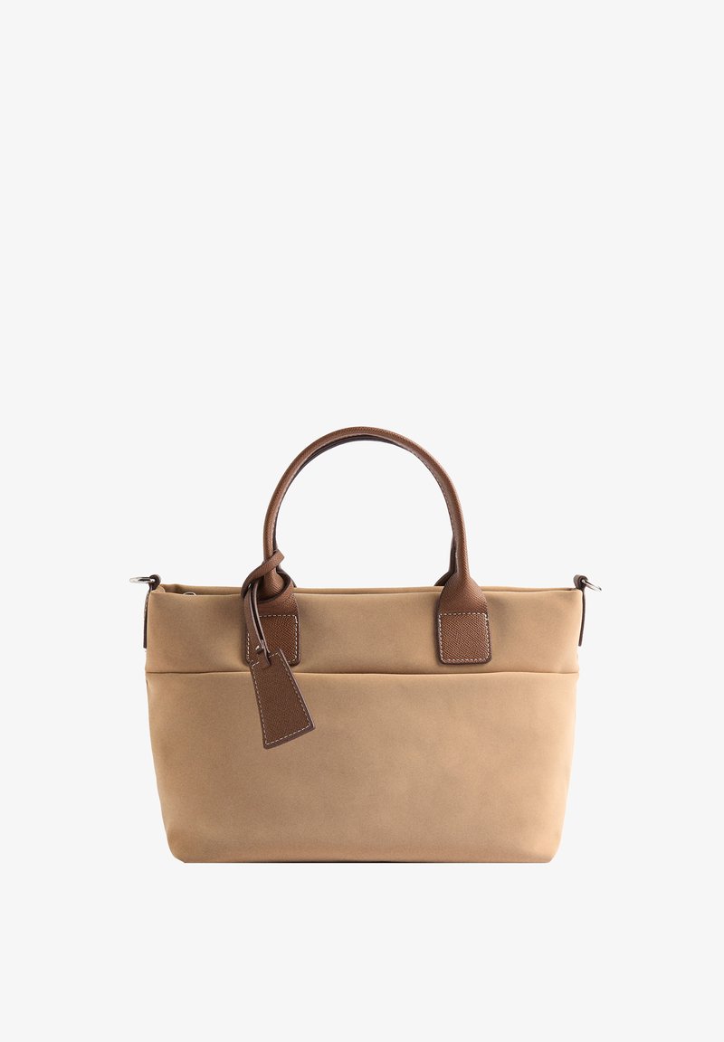 Beżowa torba na ramię z płótna z brązowymi skórzanymi akcentami i uchwytami. Posiada gładką teksturę, prostokątny kształt oraz małą metkę z boku.