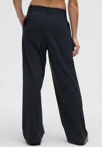 Dark navy wide-leg trousers made of smooth fabric, featuring a high waist, two back pockets, and a belt loop detail.