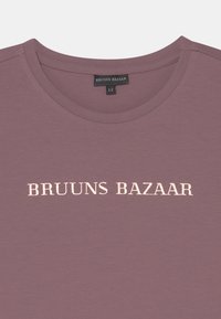 T-shirt de manga curta em tom mauve com um decote redondo, apresentando "BRUUNS BAZAAR" em relevo em texto claro na parte frontal.