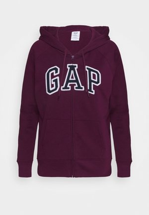 Sudadera con cremallera en color burdeos y capucha con cordón, que presenta un gran logo blanco "GAP" en la parte frontal. Tejido suave y texturizado con bolsillos frontales.