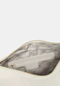 Witte leren tas met een interieur dat een gouden rits heeft. De voering heeft een logo-patroon in lichtgrijs. Inclusief een ritsvak gemarkeerd met LIU JO.