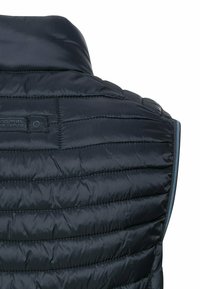 Marineblauwe gewatteerde vest met horizontaal gestikte secties, hoge kraag en een logo-label nabij de nek. Soepele, lichte stof.