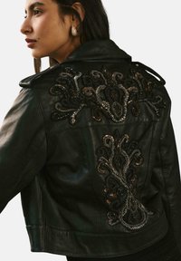 Giubbotto di pelle nera con un intricato ricamo floreale in filati metallici sulla schiena, con colletto strutturato e design aderente.