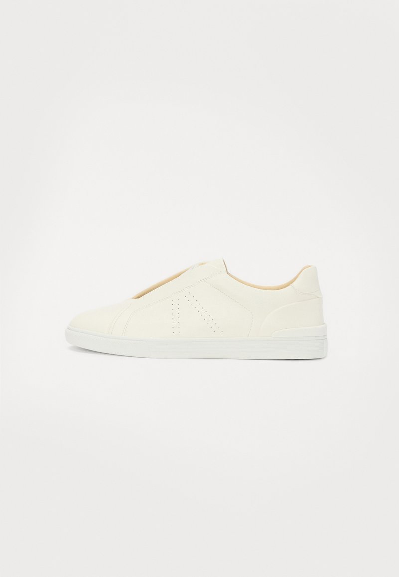 Baskets blanches à enfiler avec une texture lisse, présentant des accents perforés et un design minimaliste. Semelle en caoutchouc avec une bordure contrastante.
