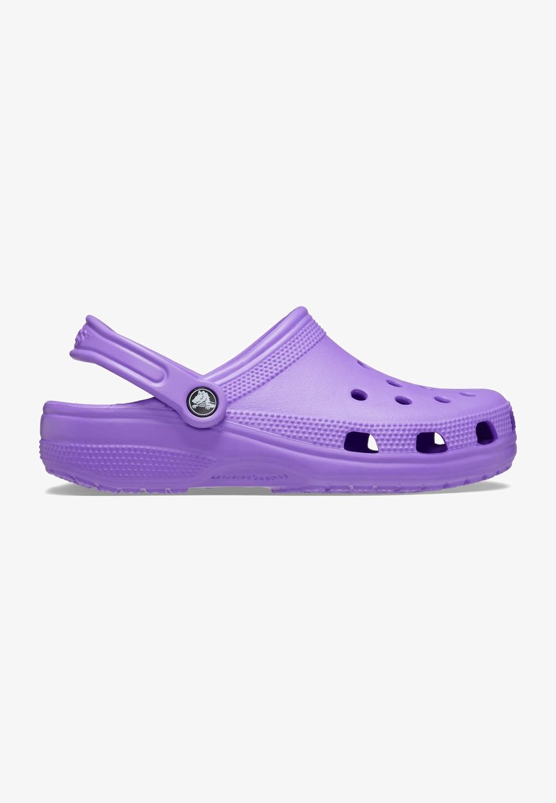 Sabot violet à enfiler avec des trous de ventilation, une semelle texturée et une bride de talon réglable avec un badge logo circulaire.