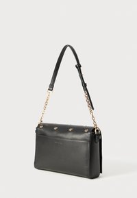 Black leather shoulder bag with a structured shape, gold chain accent, and decorative hardware on the front. Adjustable strap included.