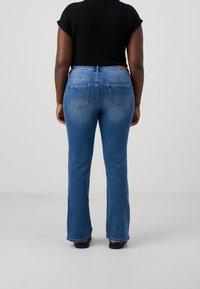 Blå utställda jeans med en blekt finish, med två bakfickor och hög midja, i kombination med en svart åtsittande topp.