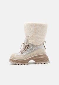 Bottes plateforme beiges avec un col en fausse fourrure, des accents en mesh et métalliques. Semelle épaisse avec texture rayée, découpe ronde et détail de laçage.