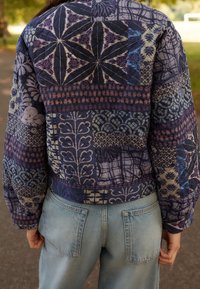 Gequilted bomberjack met een patchwork van intrikate bloemen- en geometrische patronen in tinten blauw, paars en beige; geribbelde zoom.