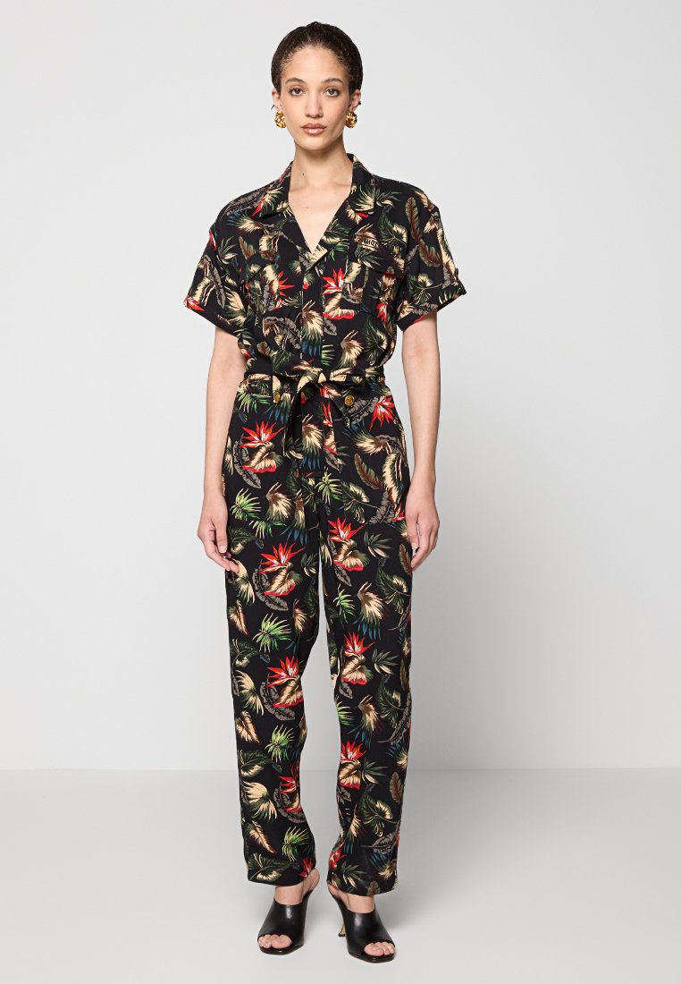 Combinaison noire à manches courtes, dotée d'un imprimé tropical vibrant. Le tissu est léger avec une taille ceinturée et un pantalon ample.