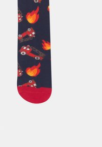 Ναυτικές κάλτσες με κόκκινη μύτη και φτέρνα, με μοτίβο από πυροσβεστικά οχήματα και φλόγες σε κόκκινο, πορτοκαλί και κρεμ, κατασκευασμένες από μαλακό, ελαστικό υλικό.