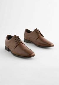 Des chaussures de ville en cuir brun avec une finition lisse, un bout pointu, un laçage et un petit talon carré. Conçues pour les occasions formelles.