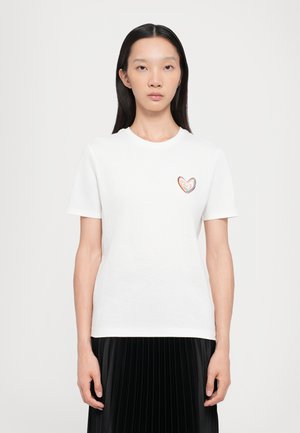 T-shirt en coton blanc avec des manches courtes, présentant un design de cœur multicolore sur le côté gauche de la poitrine. Texture lisse et coupe classique.