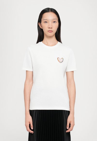 Weißes Baumwoll-T-Shirt mit kurzen Ärmeln, das ein mehrfarbiges Herzdesign auf der linken Brust zeigt. Glatte Textur und klassischer Schnitt.