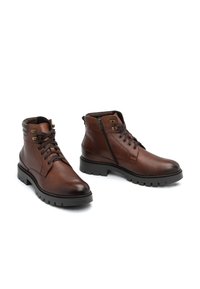 Botas de cuero marrón hasta el tobillo con un acabado texturizado, cordones en la parte delantera, cremallera lateral y suela de gran agarre.