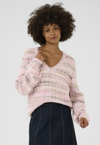 Rožainu un krēmkrāsas svītrainu adītu džemperi ar V veida kakla izgriezumu, brīvu piegriezumu un garām piedurknēm, kas izceļas ar mīkstu tekstūru un smalkām horizontālām variācijām.