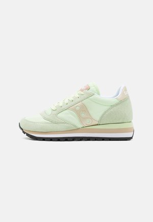 Groene suède sneaker met een gladde afwerking, crème accenten, ronde perforaties en een contrasterende zwarte rubberen zool. Vetersluiting.