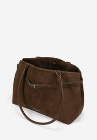 Bolso de mano de ante marrón con una textura suave, que cuenta con dos asas de cuero, un cierre de solapa y un botón a presión en el interior.