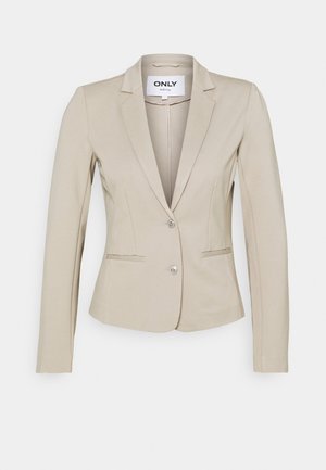 Beiger taillierter Damenblazer mit langen Ärmeln, zwei vorderen Knöpfen, gekerbtem Revers und zwei vorderen Leistentaschen auf schlichtem Hintergrund.