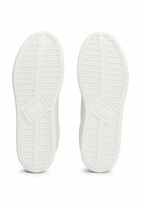 Weiße Sneaker-Sohlen mit einer strukturierten Gumm Oberfläche, die mit kleinen Kreisen und Linien gemustert sind, mit sichtbarem Branding auf der Zwischensohle.